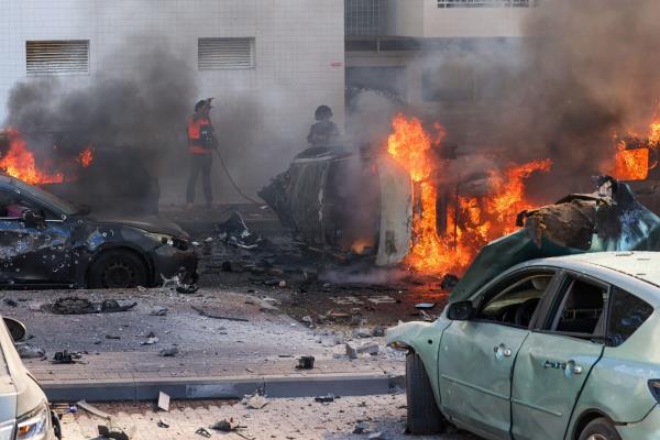 People try to extinguish fire on cars following a Hamas rocket attack from the Gaza Strip in Ashkelon, southern Israel, on Oct. 7, 2023.